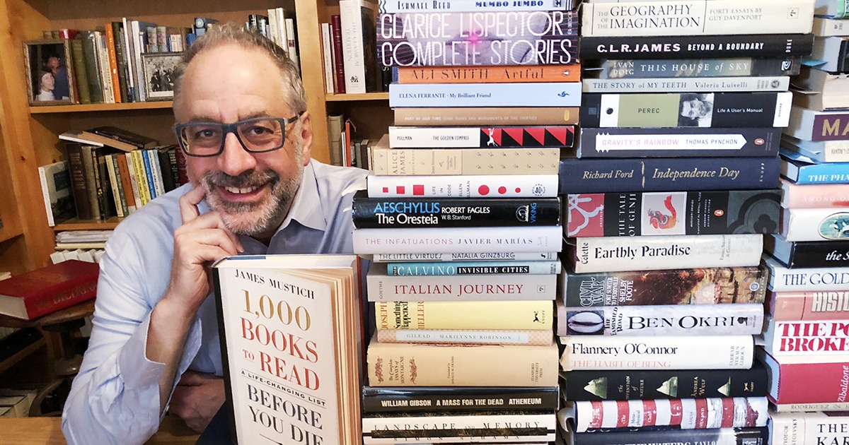 james mustichevent posing next to a pile of books